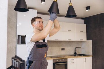 Electrician installing pendant lamps in a modern kitchen