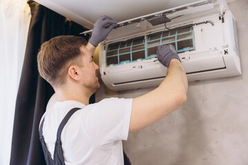 Technician repairing air conditioner mounted on wall