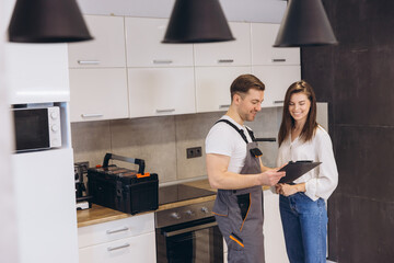 Plumber showing repair cost estimate to customer in kitchen