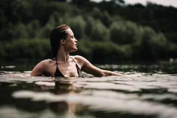 young woman swims in the pond and enjoys, rest in the lake river.