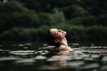 Fototapeta premium young woman swims in the pond and enjoys, rest in the lake river.