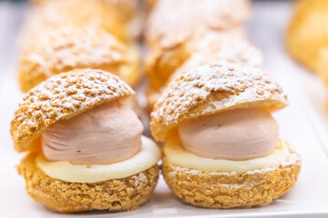 A beautifully designed restaurant communal space features sleek wooden benches positioned near a floor-to-ceiling glass facade, allowing natural light to flood the area. The warm tones of the wood