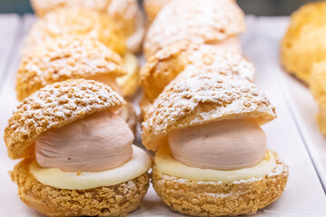 A beautifully designed restaurant communal space features sleek wooden benches positioned near a floor-to-ceiling glass facade, allowing natural light to flood the area. The warm tones of the wood
