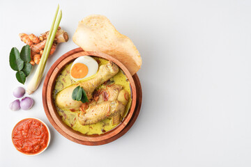 Lontong opor ayam is an Indonesian traditional dish usually served during eid Mubarak, Eid al Fitr holiday celebration with Ketupat Lebaran or rice cake dumpling and sambal chili sauce.