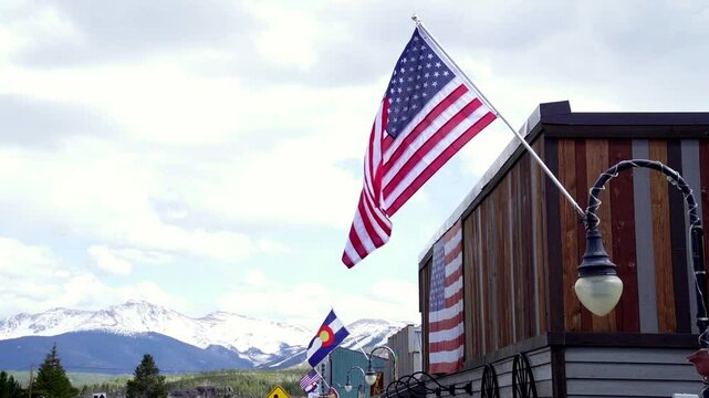 Flags of the United States and Colorado state hanging on the lamp posts in a mountain town, USA