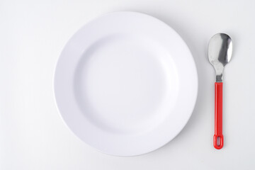 Empty white colored round shaped plate, red handle spoon and fork. Isolated on white background. Flat Lay Setup