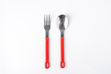 Empty white colored round shaped plate, red handle spoon and fork. Isolated on white background. Flat Lay Setup