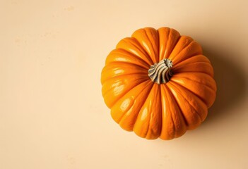 A vibrant golden orange pumpkin rests on a light beige, rustic surface , single, decor