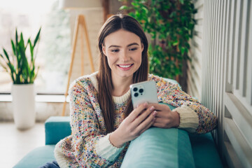 Young woman enjoying indoors leisure, casually dressed, using smartphone, cheerful atmosphere in daylight, internet of things