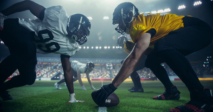 Gridiron Football Line of Scrimmage Standoff Between Two Diverse Teams Under Stadium Lights. Intense Moment of the Start of the Professional American Football Game, Players in Action During a Match - Powered by Adobe