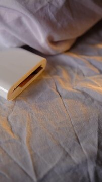 A compact pocket-sized white printer on bed prints polaroid style photo with a man in minimalist design modern technology creative process cozy atmosphere vibrant details portable convenience.