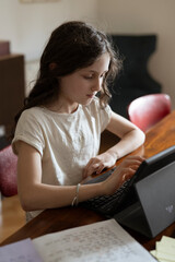 Mädchen, 10 Jahre, sitzt mit Tablet am Tisch und lernt