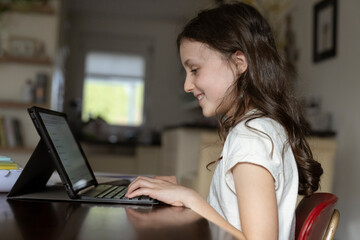 Mädchen, 10 Jahre, sitzt mit Tablet am Tisch und lernt