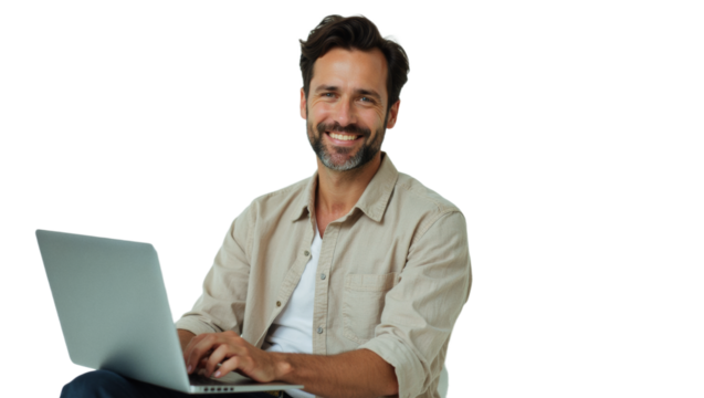Diverse people advertisement headshot: A smiling man with a beard sits comfortably using a laptop while looking directly at the camera.