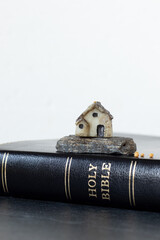 Miniature house on rock on top of holy bible book. Close-up. Copy space. Gospel parable of Jesus...