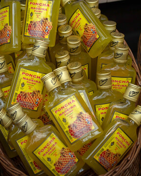 FUNCHAL, MADEIRA - FEBRUARY 03, 2025:  Bottles of rum punch (Poncha da Madeira)  in a basket on a market stall