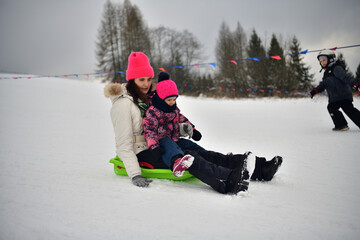 Family tobogganing down a snowy hill during winter vacation