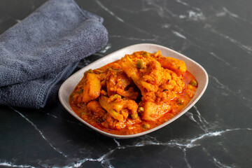 Aloo Phulkopir Dalna is a Bengali potato and cauliflower curry, cooked with spices, tomatoes, and ginger in a rich gravy.
