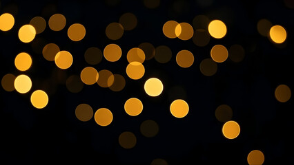 A vibrant, blurry bokeh effect of golden-orange circles of light against a deep black background, capturing the diffused glow of out-of-focus light sources.