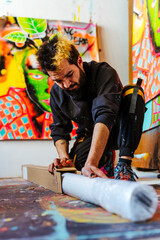 Artist Preparing a Blank Canvas in Creative Studio. An Argentine artist unrolls a blank canvas in his vibrant studio, getting ready to start a new abstract artwork.

