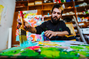 Close-Up of Artist Mixing Paint on a Palette. An Argentine artist dips a brush into blue paint on a...