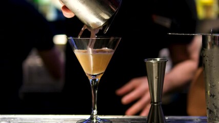 Bartender pours Mexican martini from shaker into a dressed glass, slow motion 4K. High quality