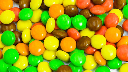Colorful assortment of hard shelled candies piled together on a white surface