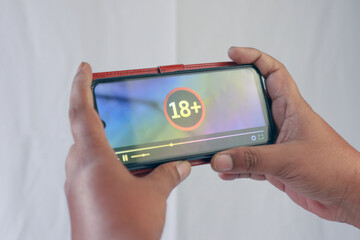 Hand Holding Smartphone with 18 Plus Warning Screen