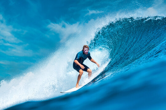 Male surfer on a blue wave at sunny day