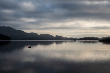 Early morning winter photo of Loch Lomond, Scotland, from the tiny picturesque village of Luss; with beautiful reflexion of clouds and mountains in the lake