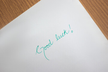 Good luck note written with hand on white paper on the table 