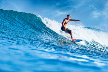Male surfer on a blue wave at sunny day