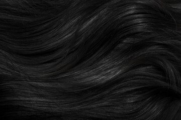 Brunette or black hair. Female long dark hair in black. Beautifully laid curls. Closeup texture in a dark key. Hairdressing, hair care and coloring. Shading gray hair. Background with copy space.