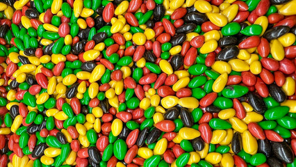 Nuts in multi-colored chocolate glaze are lying in bulk.