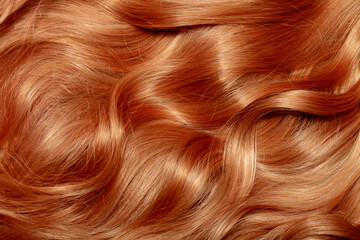 Red hair close-up as a background. Women's long orange hair. Beautifully styled wavy shiny curls....
