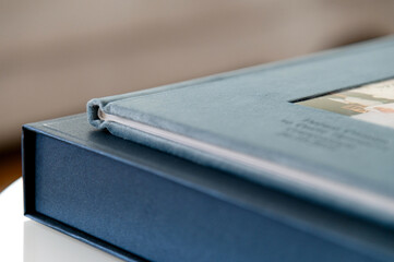 Close up of a blue velvet photo album on a blue box on a white surface displaying a family photo
