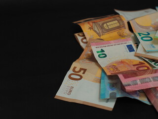 Close-up of scattered euro-coupons, paper texture and security features are clearly visible. There is space for text