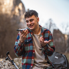 man hiker left voice message mobile phone on hiking trip near rocks