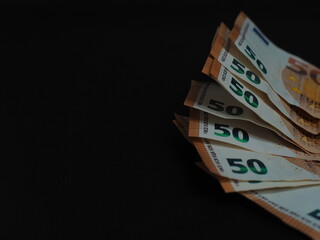 50 Euro bills are partially stacked one on top of the other, creating an effect of depth. The black background emphasizes the details
