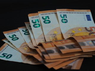 50 Euro bills are arranged in a fan on a black background. Design elements, denominations and security features are clearly visible.