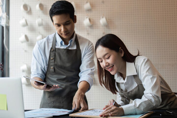 Planning and Coffee Shop Strategy. Baristas collaborating on promotional ideas for their cafe,...