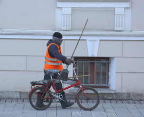 A street cleaner with a bicycle walks along the sidewalk along the wall, Isaac's Square, St. Petersburg, Russia, March 17, 2025 