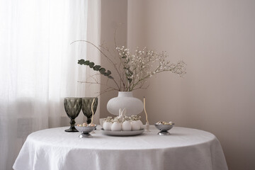 A beautifully arranged table with delicate flowers, desserts, and vintage glassware, creating a serene easter atmosphere.