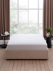Elegant double bed with a gray fitted sheet on mattress and two bedside tables in front of a large window with brown curtains in a modern style bedroom. Front view photo. Suitable for mockup
