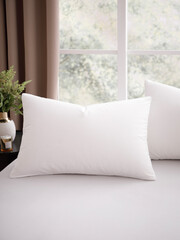 Bed with two pillows in pillow cases, covered with snow-white sheets, in a modern, bright bedroom, with a large window, decorated with brown curtains. Close-up photo. Suitable for mockup.