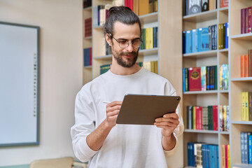Young handsome man using digital tablet inside library office