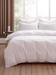 Bedroom with large window decorated with curtains. Bed covered with a white duvet, four pillows with pillowcases and a bedside table on the left side of the bed. Front view photo. Suitable for mockup