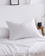 The bed with pillow and white sheets, elegantly draped over a mattress in the interior of a modern bedroom. One corner of the mattress is visible. Close-up photo. Suitable for mockup