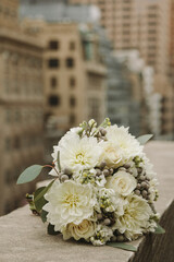 Elegant white flower bouquet displayed on a stone ledge in an urban setting during the daytime