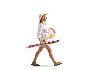 Woman carrying a ball and beach umbrella and walking